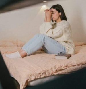 Woman in White Sweater and Blue Denim Jeans Sitting on Bed