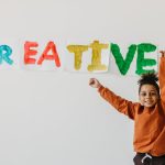 A Boy Showing the Art Project Posted on the White Wall